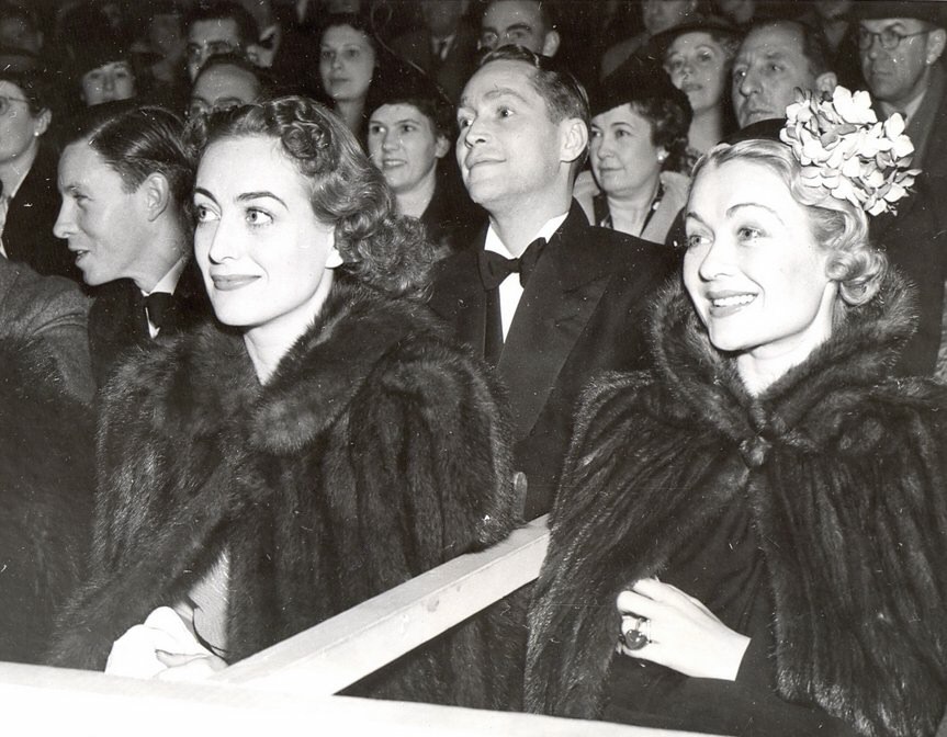 1937. At a tennis match (yes, in furs) with Franchot Tone and Constance Bennett.