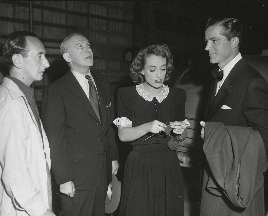August 1947. On the set of 'Daisy Kenyon' with columnists Leonard Lyons and Walter Winchell, and co-star Dana Andrews.