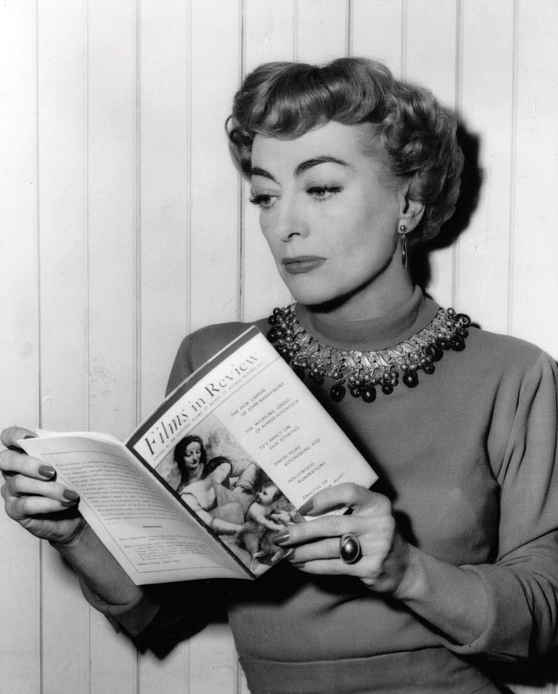 1953. On the set of 'Torch Song' reading 'Films in Review.'