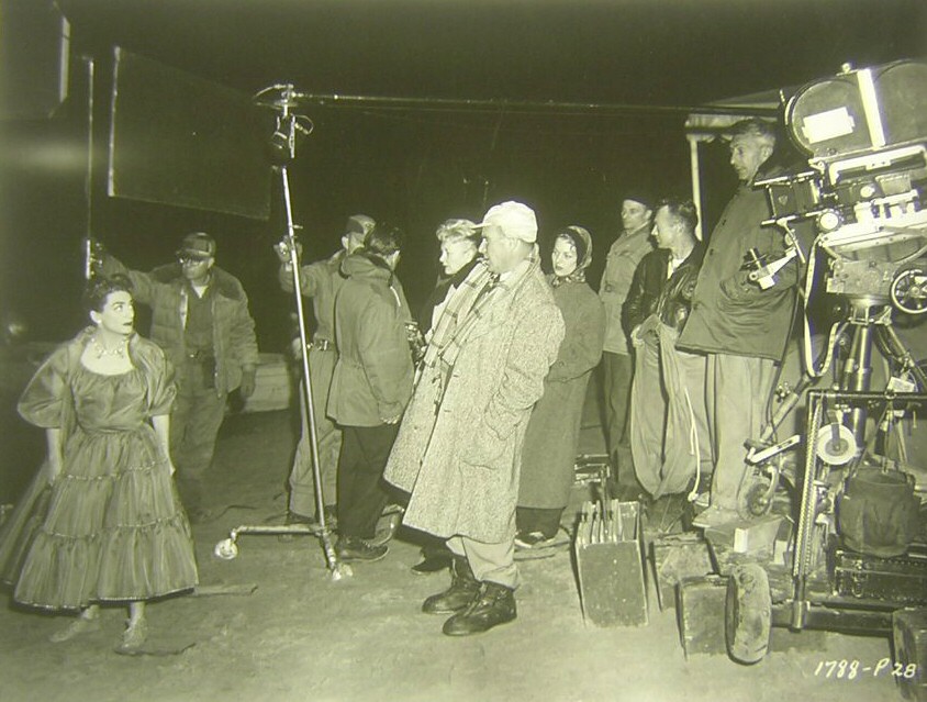 1955. On the set of 'Female on the Beach' with cinematographer Charles Lang (in the white cap).