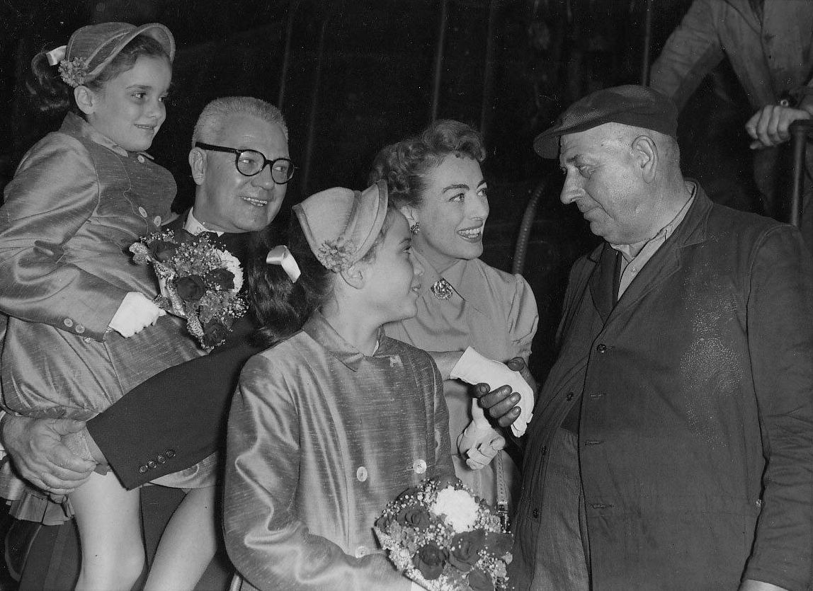 August 1956 at London's Paddington Station with husband Al Steele, twins, and train conductor.