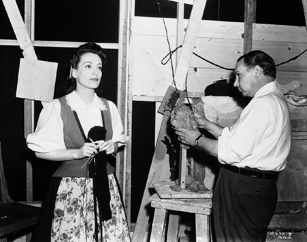 1941. On the set of 'A Woman's Face,' posing for Yucca Salamunich's bust of herself.